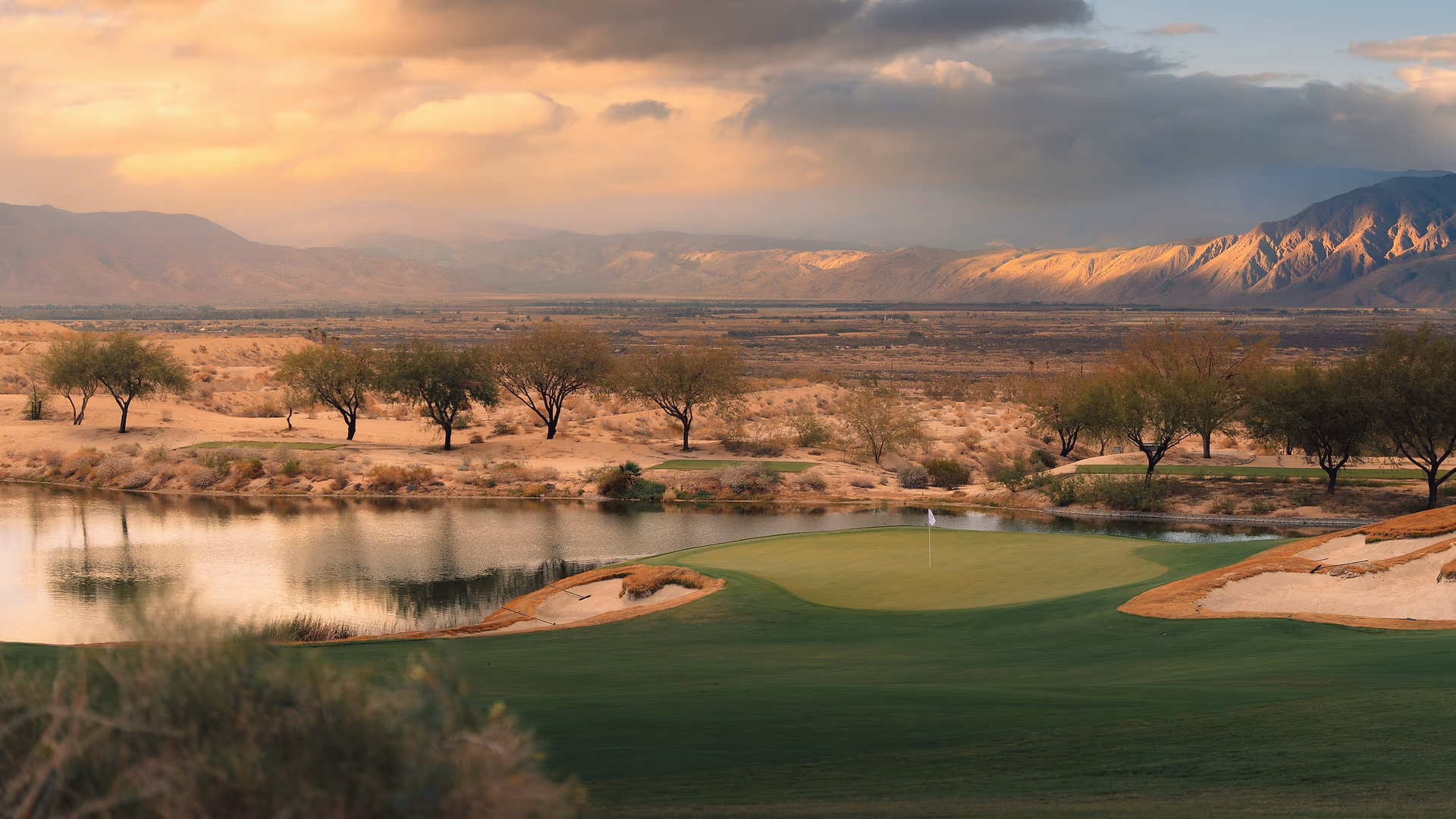 Golden hour at Rams Hill Golf Club, with a green and water set against the Borrego Springs desert and mountains.