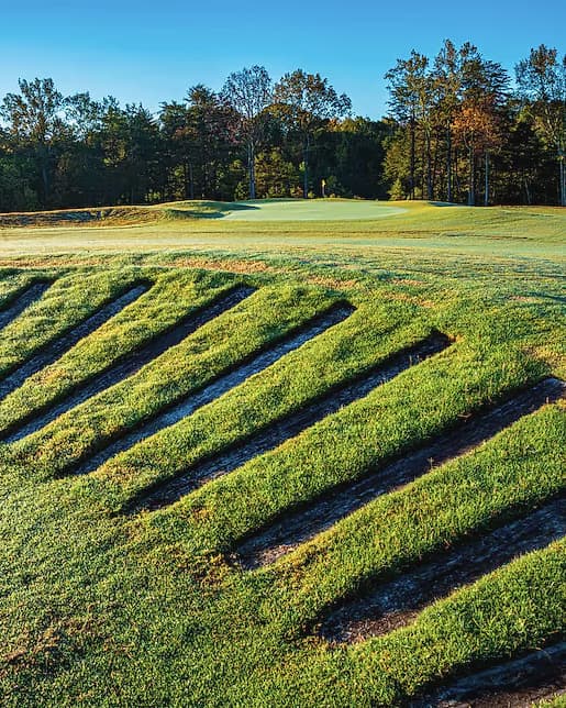 Stacked railroad-tie bunker faces stepping down a hillside at Cutalong, under autumn hardwoods.