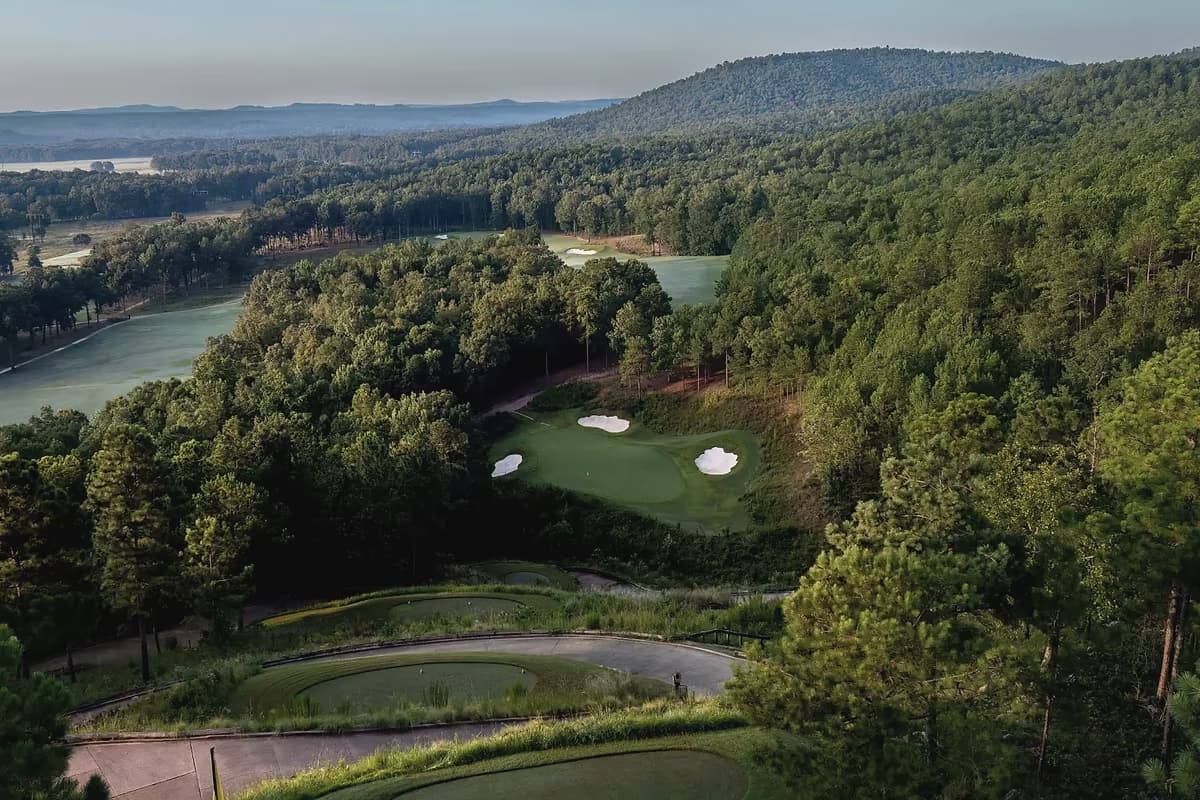 Looking down onto a green and its bunkers at FarmLinks at Pursell Farms from well above, enclosed by Alabama hardwood forest.
