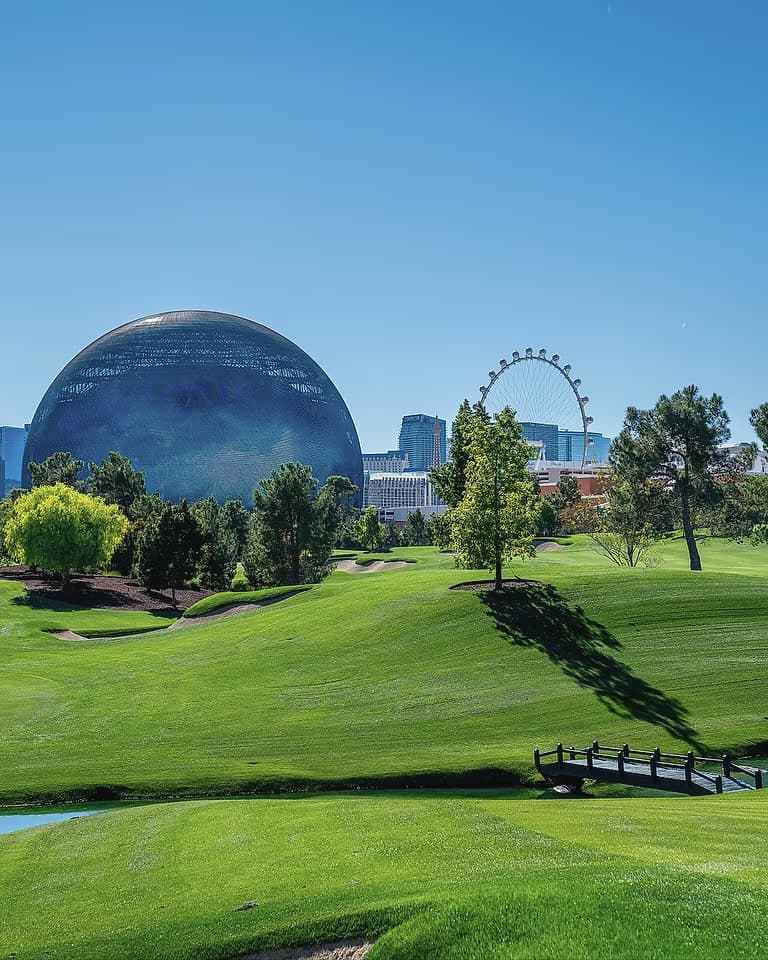 The Sphere rising above the fairway at Wynn Golf Club, with the High Roller wheel and the Las Vegas skyline beyond.