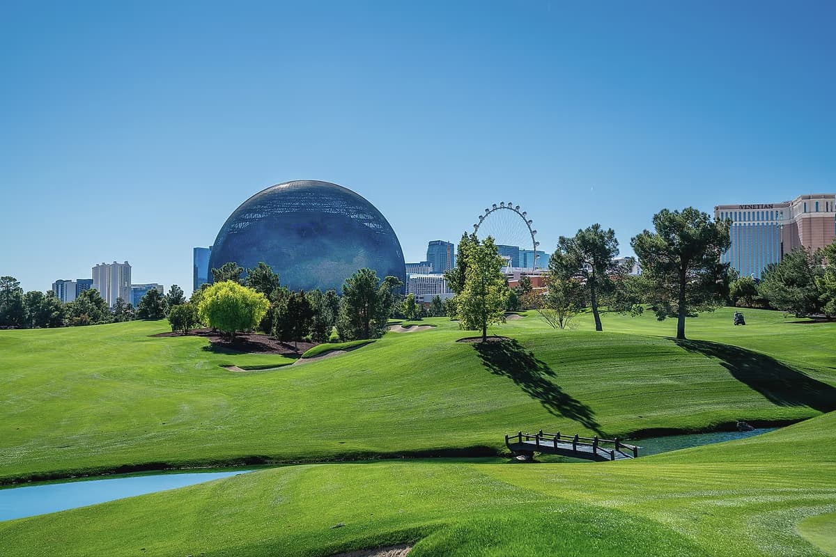 The Sphere rising above the fairway at Wynn Golf Club, with the High Roller wheel and the Las Vegas skyline beyond.